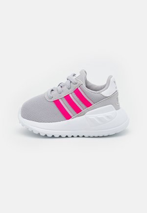 Grå mesh-sneaker med hvid sål og lyserøde tre striber, med grå snørebånd og polstret krave for komfort.