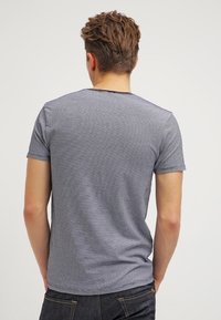 Gråstribet t-shirt med korte ærmer og rund halsudskæring, der har en blød tekstur og en afslappet pasform, set bagfra.