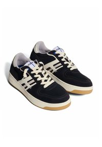 Sneakers in suede nera con lacci bianchi, dettagli color crema e suola in gomma naturale. Presentano cuciture decorative e un logo sul lato.