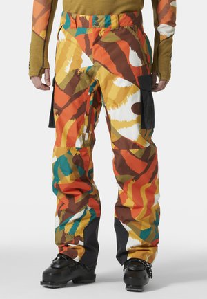 Pantalones de esquí coloridos con un patrón abstracto en naranja, marrón, amarillo y azul verdoso. Fabricados con material duradero, cuentan con bolsillos tipo carga y cintura ajustable.