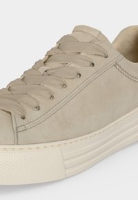 Baskets en daim beige avec des lacets assortis et une semelle blanche épaisse et texturée visible de profil.