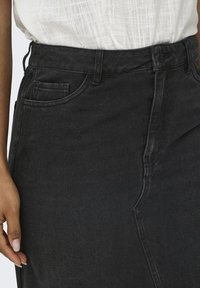 Zwarte denim rok met hoge taille, zijzakken en subtiele stikdetails. De stof heeft een gladde textuur met een lichte rek.