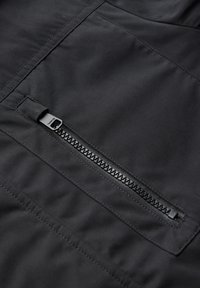 Černá zateplená bunda s horizontální kapsou na zip, texturovaným zipem, hladkým materiálem a prošívanými detaily.