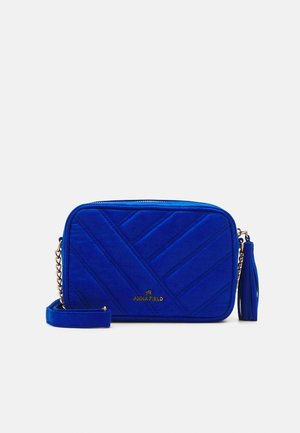 Rektangulær blå crossbody-taske med diagonalt quiltet mønster, guldkæde-rem, lynlåstræk med kvast og "ANNA FIELD"-logo på forsiden.