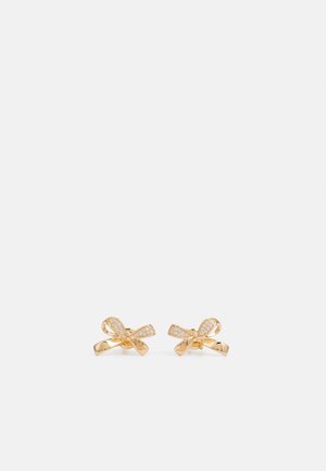 Pendientes en forma de lazo de color dorado con pequeños cristales incrustados, exhibidos uno al lado del otro sobre un fondo blanco.