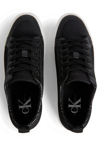 Svarta sneakers med en texturerad mesh-övre, släta syntetiska accenter, vit gummisula och kontrasterande sömmar längs kanterna.