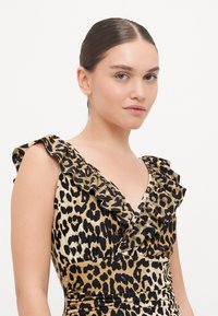 Vestido de estampado de leopardo com decote em V profundo, mangas com babados e cintura justa. O material é suave com um leve brilho.