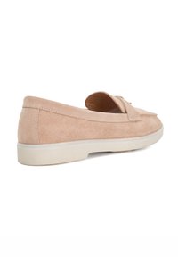 Suede slip-on shoe in light pink with a rounded toe, subtle tassel detail, and a white rubber sole. Smooth texture and minimal design.
