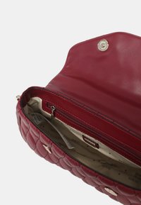 Rode quilted leren handtas met een ritsvak en merkgevoerd interieur. Voorzien van een drukknoopsluiting en gouden accenten.