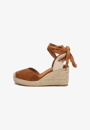 Cuña de espadrille de ante marrón con suela de yute trenzado, diseño de punta abierta y cintas para el tobillo. Acento de tela texturizada en el talón.