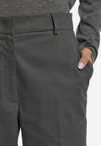 Dunkelgraue, maßgeschneiderte Hose mit glatter Textur, seitlichen Taschen und flachem Vorderdesign. Klarer Bund mit Gürtelschlaufen.
