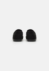 Black suede loafers with a rounded back and low rubber sole, featuring minimal stitching and a smooth texture.