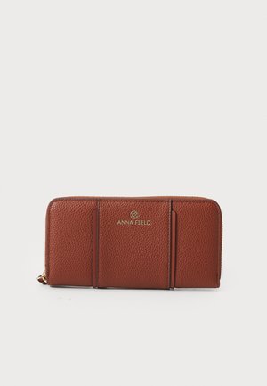 Hnedá textúrovaná kožená peňaženka so zlatým brandingom. Má viacero priehradiek na karty a zipsové uzatváranie. Obdĺžnikový tvar s čistými líniami.