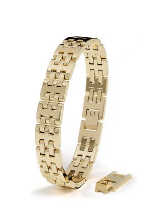 Goldfarbenes Metall-Uhrarmband mit verbundenen rechteckigen Segmenten und einem abgelösten Verschlussstück, das neben dem Armband auf einem weißen Hintergrund liegt.