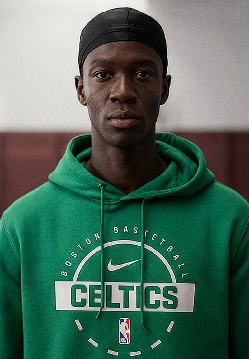 Fiatal férfi, fekete fejkendővel és zöld Boston Celtics NBA kapucnis pulóverrel, semleges arckifejezéssel, közvetlenül a kamerába néz.