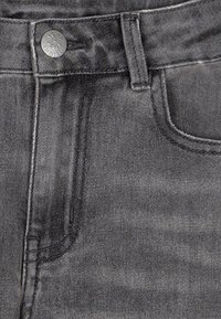 Tessuto di denim grigio con chiusura a bottone metallico, passanti per cintura e una tasca frontale con dettagli di cucitura visibili.