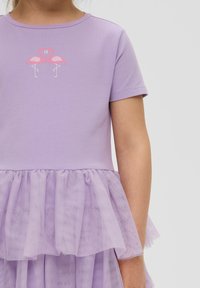 Fioletowa sukienka z krótkim rękawem, zdobiona haftem w flamingi, oraz warstwową spódnicą z tiulu, tworzącą teksturowany, zabawny design.