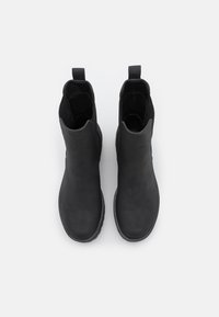 Black ankle boots made of smooth, matte leather with a rounded toe and flat rubber sole. Features twin pull tabs for easy wear.