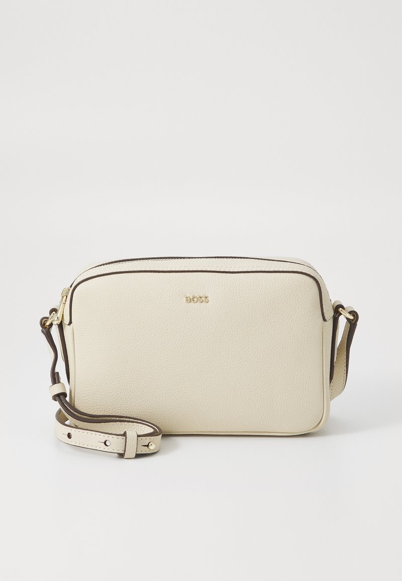 Borsa a tracolla in pelle crema con rifiniture marroni, logo dorato, forma rettangolare, texture liscia e tracolla regolabile. Chiusura con zip.