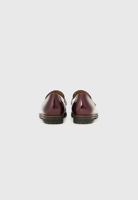 Burgundijas lakotās ādas loafers ar noapaļotu purngalu, zemu profilu un teksturētu melnu gumijas zoli, ar gludu apdari un smalkām šuvēm.