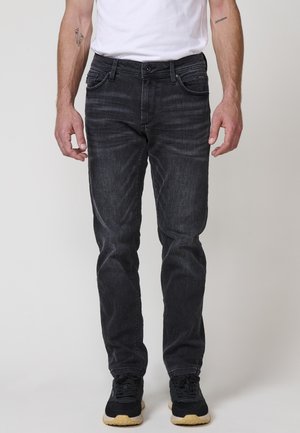Vaqueros de mezclilla gris oscuro con corte recto, diseño de cinco bolsillos, un ligero desgaste y detalles en hardware negro, combinados con zapatillas negras.