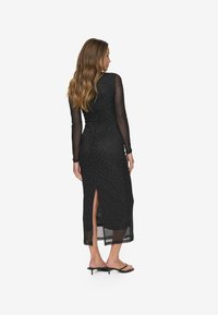 Mustikas pikkvarrukas kleit, millel on läbipaistev kiht, kaunistatud väikeste nippudega. Sellel on külgmine lõhk ja sobiv siluett.