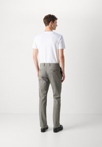 Grå chinos med en skræddersyet pasform, sammen med en ensfarvet hvid t-shirt med korte ærmer. Designet har lommer og en glat stofstruktur.