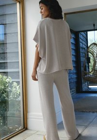 Lightweight, striped loungewear set in beige and cream, featuring a loose, short-sleeve top and wide-leg pants, soft texture, relaxed fit.