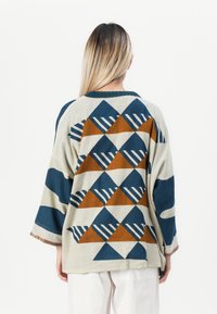 Chemise en coton lâche avec des motifs géométriques en bleu marine, orange et crème ; dotée d'un col rond et de manches trois-quarts.