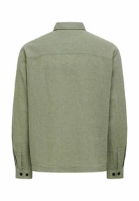 Chemise en lin vert olive à manches longues avec poignets boutonnés et empiècement droit dans le dos, vue de dos sur fond blanc.