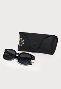 Ochelari de soare Ray-Ban negri cu rame pătrate, lentile gri și detalii metalice argintii. Însoțiți de un toc texturat negru asortat, având logo-ul.