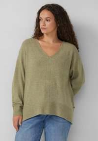 Olijfgroen, gebreid sweater met een V-hals en geribbelde manchetten. Kenmerkt zich door een geperforeerd patroon in het midden en een iets langere achterzoom.