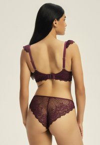 Burgundowy komplet bielizny koronkowej składający się z biustonosza z regulowanymi ramiączkami i falbankami, w zestawie z dopasowanymi przezroczystymi koronkowymi majtkami.