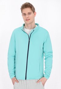 Šviesiai mėlyna zip-up striukė su aukštu apykakle, kontrastinga tamsiai mėlyna užtrauktuku ir šoninėmis kišenėmis, pagaminta iš lygaus audinio, tinkamo aktyviam sportui.