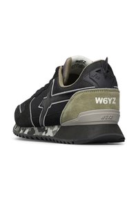 Černé a olivově zelené tenisky s maskáčovou podrážkou, logo W6YZ na patě a texturované semišové a síťované materiály.