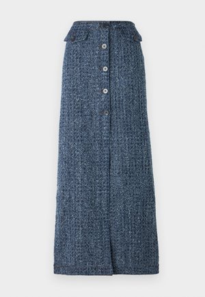 Sininen tweed-takki, jossa on kaksi rintataskua. Yhdenmukaisen pitkän hameen edessä on halkio. Kantaa vaaleanruskeaa nahkasta olkalaukkua.