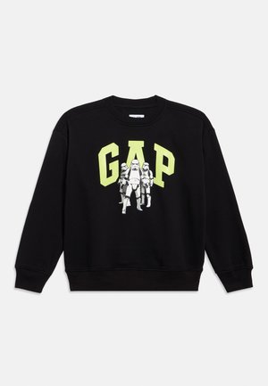 Felpa nera con la scritta "GAP" in lettere gialle riflettenti e in grassetto. Presenta una grafica con tre stormtrooper. Polsini e orlo a costine.