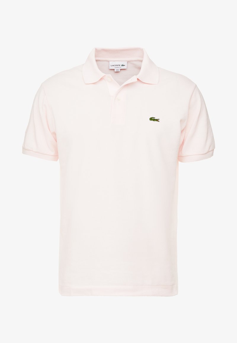 Polo tričko v svetlo ružovej bavlne s klasickým golierom, krátkymi rukávmi a zeleným vyšitým logom Lacoste na ľavej hrudi.