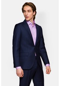 Granatowa marynarka w kratę z dwoma guzikami i ostrymi klapami, połączona z jasnofioletową koszulą z standardowym kołnierzykiem.