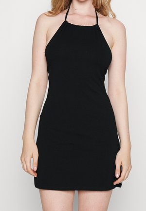 Sort halterkjole med en figursyet silhuet. Har en rynket halsudskæring og tynde stropper. Stoffet virker glat og strækbart.