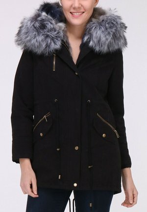 Parka noire avec un col en fourrure grise, ornée de zips dorés, d'une taille à cordon et de deux poches avant avec fermetures zippées.