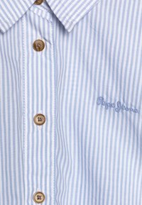 Camicia a strisce blu chiaro e bianca realizzata in tessuto con una finitura liscia, dotata di bottoni marroni e un logo ricamato, "Pepe Jeans."