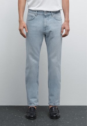 Light blue straight-leg denim jeans with a classic five-pocket design and a slight fade, paired with black loafers.