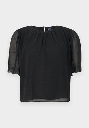 Mustast lühikeste varrukatega pluus, millel on õhulised šifoonist varrukad ja peen tikand mansettidel, voltidega kaelus ning GAP-i silt seljal.