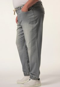 Pantalones de algodón gris claro con cintura elástica, cordón, bolsillos laterales y tobillos con puños, combinados con zapatillas blancas.