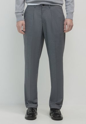 Graue maßgeschneiderte Hose aus strukturiertem Stoff, mit Falten, einem einzelnen Knopfverschluss und geraden Beinen, kombiniert mit schwarzen Schuhen.