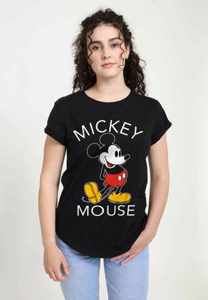 T-shirt nera in cotone con una grafica di Topolino in pantaloni rossi e scarpe gialle, con testo che recita "TOPOLINO" in bianco.