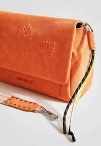 Borsa a tracolla arancione con texture e design in rilievo, patta pieghevole e manico staccabile con moschettone e dettagli colorati.
