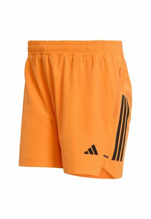 Pomarańczowe sportowe krótkie spodenki wykonane z lekkiego materiału. Posiadają czarny wzór z trzema paskami, elastyczny pas oraz boczną kieszeń na zamek.