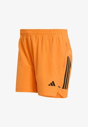 Pomarańczowe sportowe krótkie spodenki wykonane z lekkiego materiału. Posiadają czarny wzór z trzema paskami, elastyczny pas oraz boczną kieszeń na zamek.